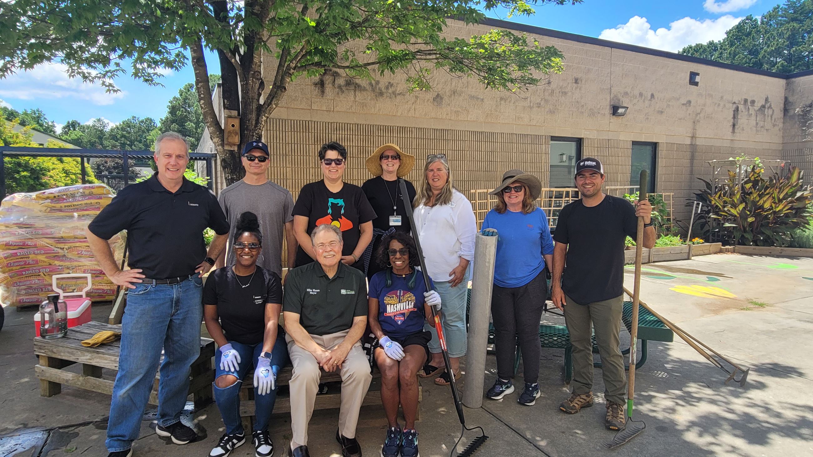 Group of volunteers and the mayor in front of a garden installation