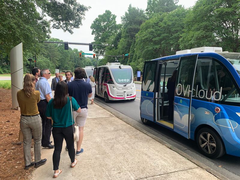 Two autonomous vehicles and some people at Curiosity Lab.